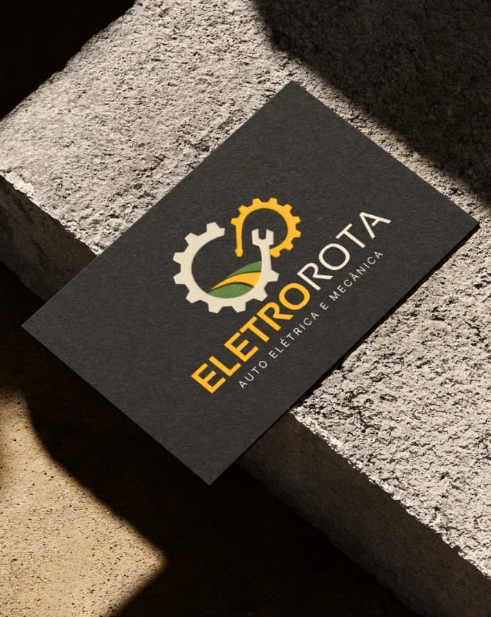 Cartão de visita da marca EletroRota Auto Elétrica e Mecânica sobre superfície de concreto